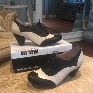 Tie saddle shoe with heal. Leather upper and sole. Black and cream color.